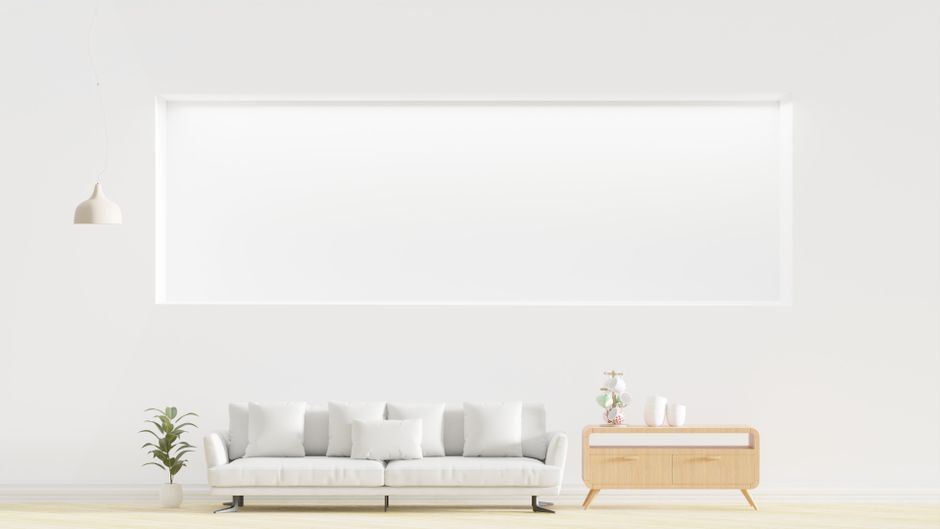 Bright, minimalist living room with a modern couch, dresser, and indoor plant.